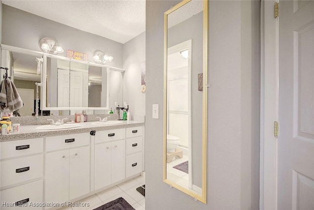 bathroom featuring vanity, toilet, a textured ceiling, and tile patterned flooring