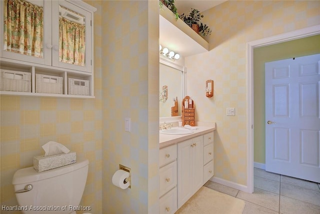 bathroom featuring tile patterned flooring, wallpapered walls, baseboards, toilet, and vanity