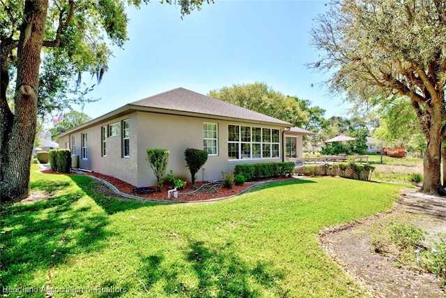 view of side of property with stucco siding and a lawn