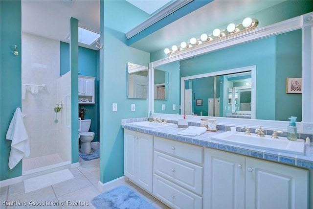 bathroom with a sink, tiled shower, toilet, and tile patterned floors