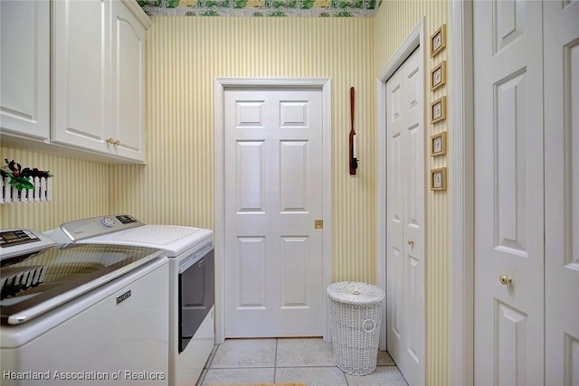 washroom featuring cabinet space, light tile patterned floors, washing machine and dryer, and wallpapered walls