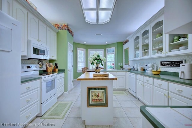 kitchen featuring a kitchen island, white appliances, light tile patterned flooring, white cabinets, and glass insert cabinets