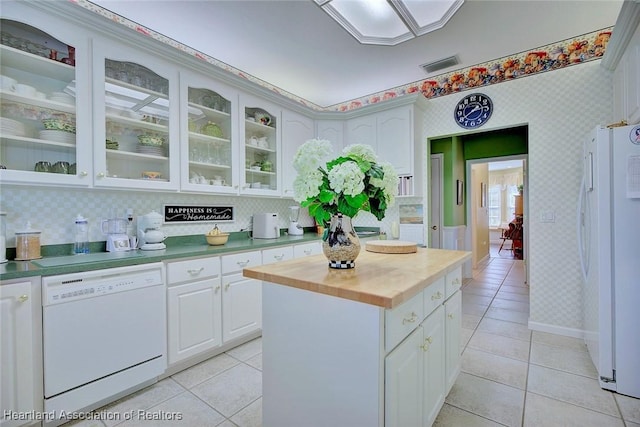 kitchen with visible vents, white appliances, light tile patterned flooring, wallpapered walls, and glass insert cabinets