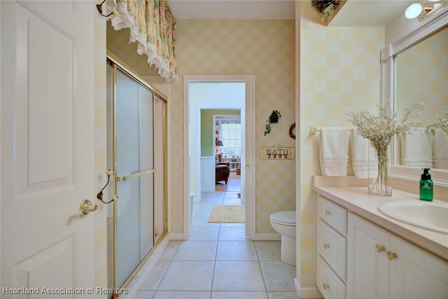 bathroom with vanity, wallpapered walls, a shower stall, tile patterned floors, and toilet