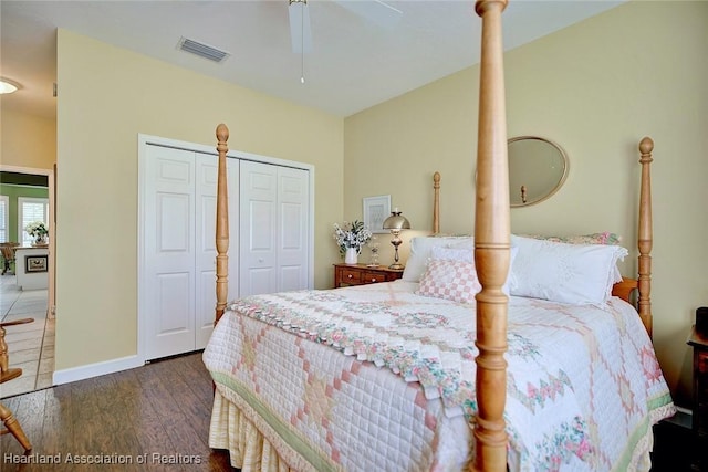 bedroom with a ceiling fan, visible vents, wood finished floors, baseboards, and multiple closets