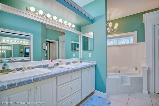 full bath with tile patterned floors, a garden tub, a chandelier, and a sink