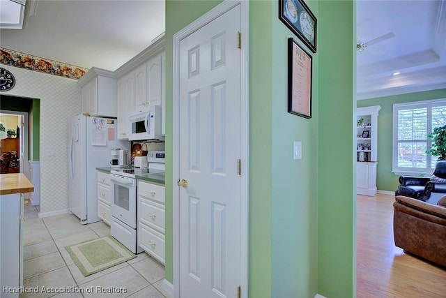 kitchen with white appliances, wallpapered walls, light tile patterned flooring, white cabinets, and open floor plan