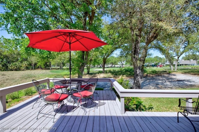 wooden deck with outdoor dining area and a yard