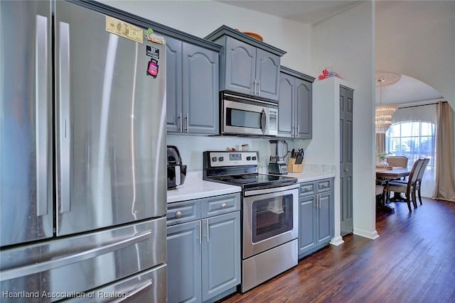 2200 W Geneva Rd, Avon Park, FL 33825 - kitchen with appliances with stainless steel finishes, gray cabinetry, a chandelier, dark wood finished floors, and arched walkways