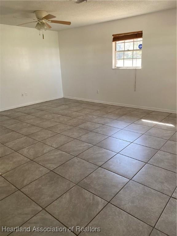 empty room with ceiling fan, light tile patterned floors, and a textured ceiling