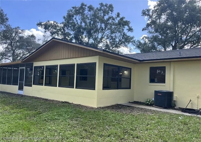 view of home's exterior featuring cooling unit, a sunroom, and a lawn