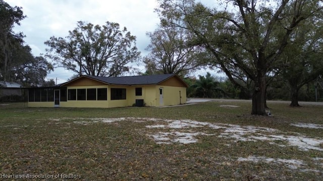 view of property exterior with a yard, a sunroom, and central air condition unit