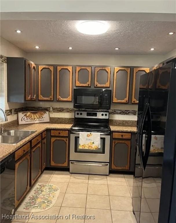 kitchen with light tile patterned floors, sink, a textured ceiling, and black appliances