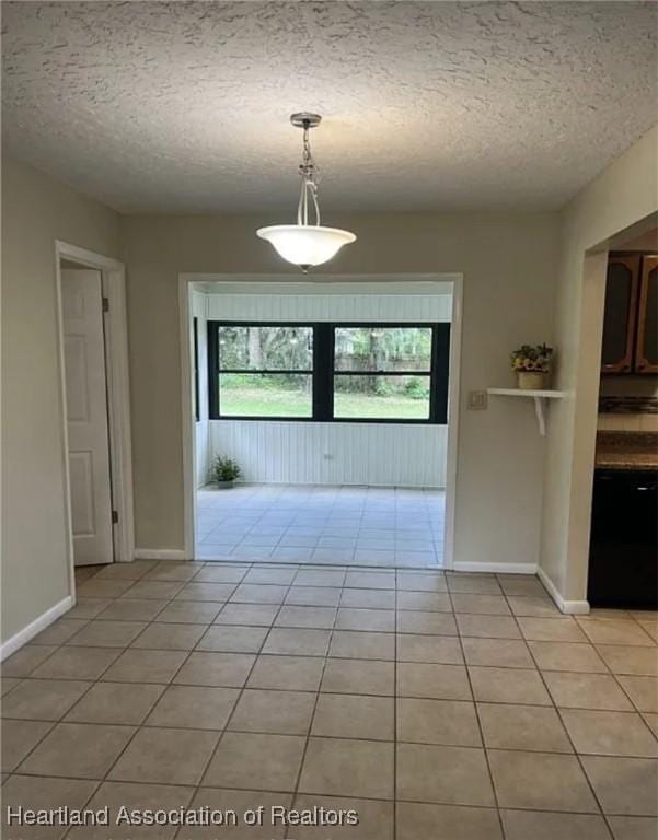 unfurnished dining area featuring a textured ceiling and light tile patterned floors