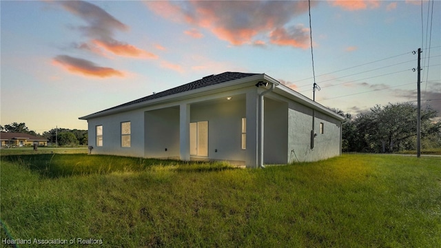 property exterior at dusk featuring a lawn