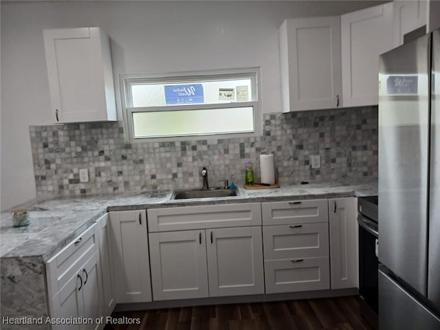 kitchen with white cabinetry, stainless steel refrigerator, tasteful backsplash, and sink