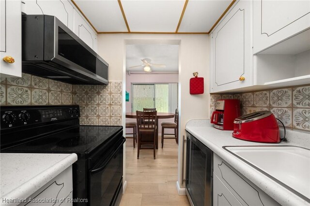 2111 Lakeview Dr Unit 1A, Sebring, FL 33870 - kitchen featuring black range with electric stovetop, stainless steel microwave, beverage cooler, light countertops, and white cabinetry