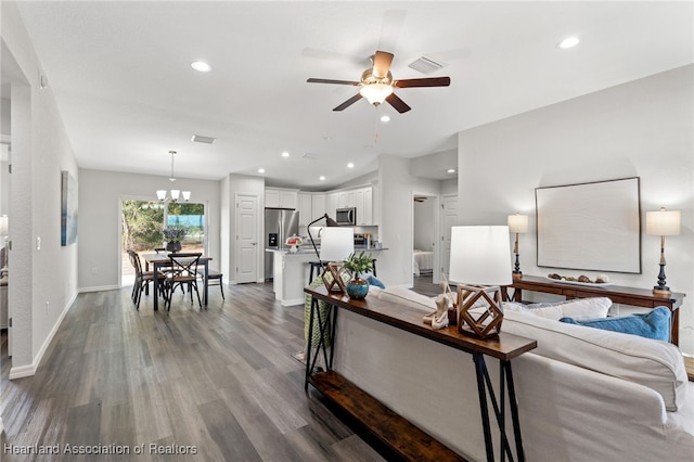 living room with ceiling fan with notable chandelier and wood-type flooring