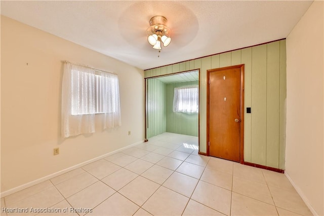 spare room featuring ceiling fan, light tile patterned floors, and a healthy amount of sunlight