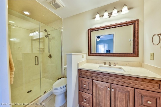 bathroom featuring tile patterned flooring, vanity, toilet, and a shower with door