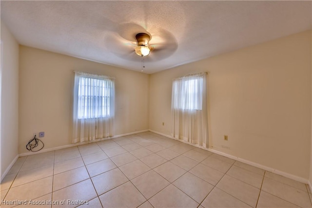 empty room featuring ceiling fan, light tile patterned floors, and a textured ceiling