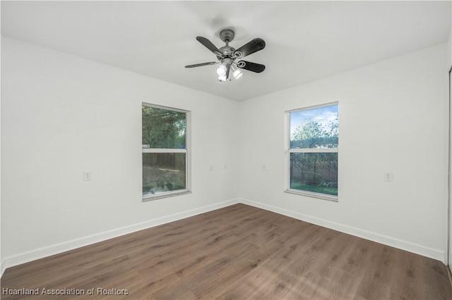 spare room featuring ceiling fan, a healthy amount of sunlight, and dark hardwood / wood-style floors