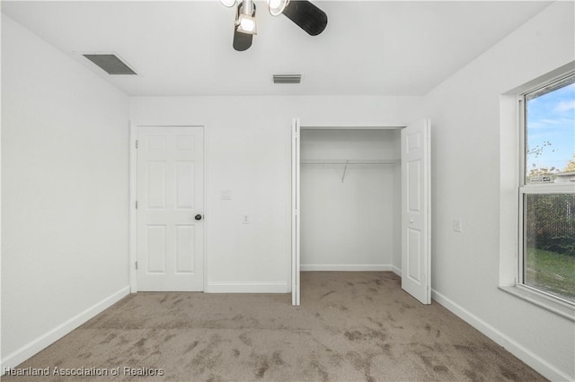 unfurnished bedroom with ceiling fan, a closet, light carpet, and multiple windows