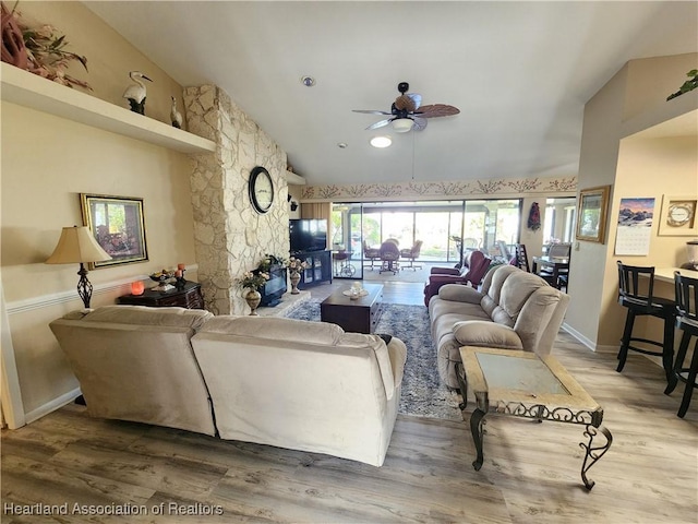 living room featuring ceiling fan, a fireplace, wood-type flooring, and vaulted ceiling