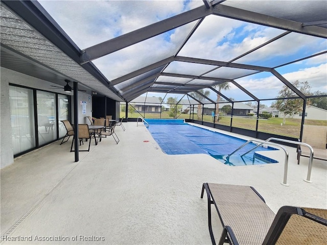 view of pool featuring glass enclosure and a patio