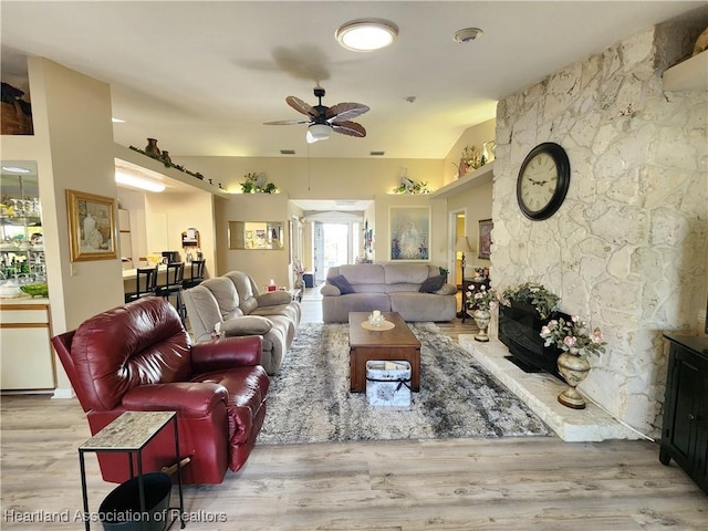 living room with a fireplace, light hardwood / wood-style floors, and ceiling fan