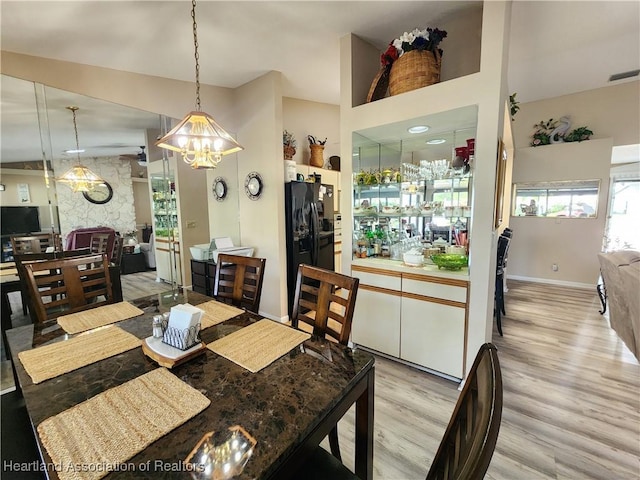 dining room with light hardwood / wood-style floors, lofted ceiling, and a notable chandelier