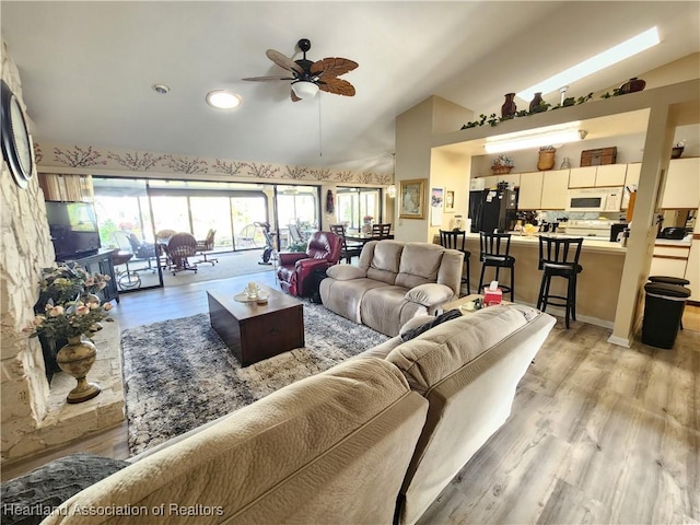 living room with ceiling fan, light hardwood / wood-style flooring, and lofted ceiling