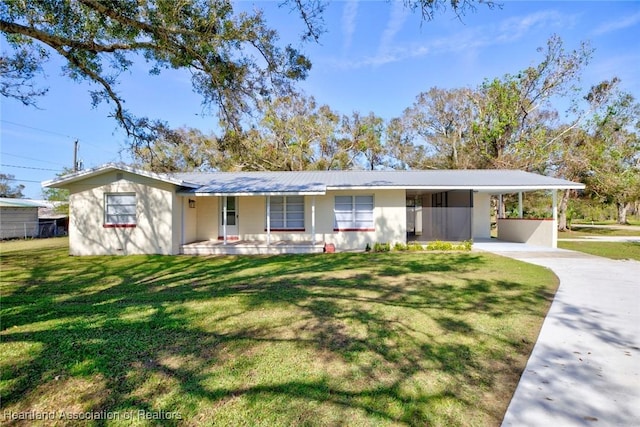 ranch-style house featuring covered porch, a carport, and a front yard