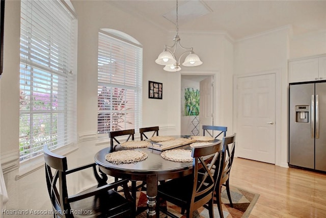 dining space with light hardwood / wood-style floors, crown molding, and a notable chandelier