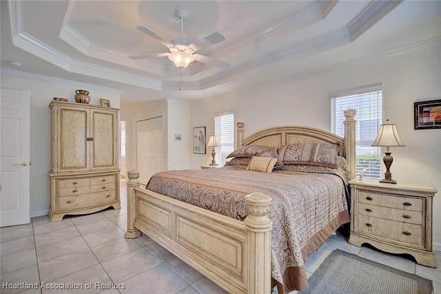 bedroom featuring crown molding, ceiling fan, light tile patterned floors, a tray ceiling, and a closet