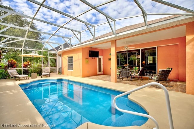 view of pool featuring glass enclosure, ceiling fan, and a patio