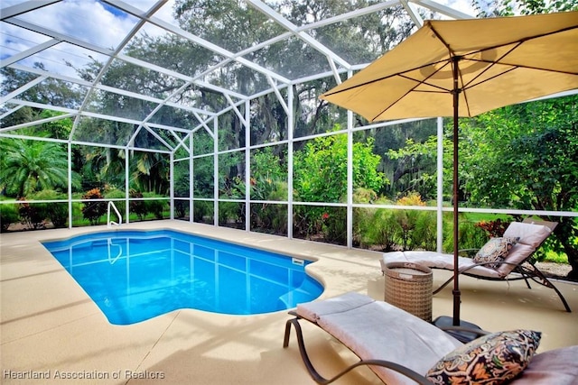 view of pool with glass enclosure and a patio area