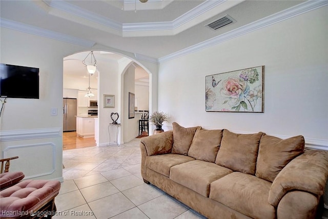 tiled living room featuring a tray ceiling, ceiling fan, and ornamental molding