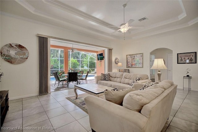 living room with ceiling fan, light tile patterned flooring, a raised ceiling, and ornamental molding