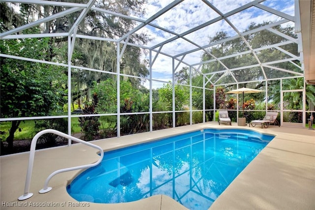 view of pool featuring glass enclosure and a patio