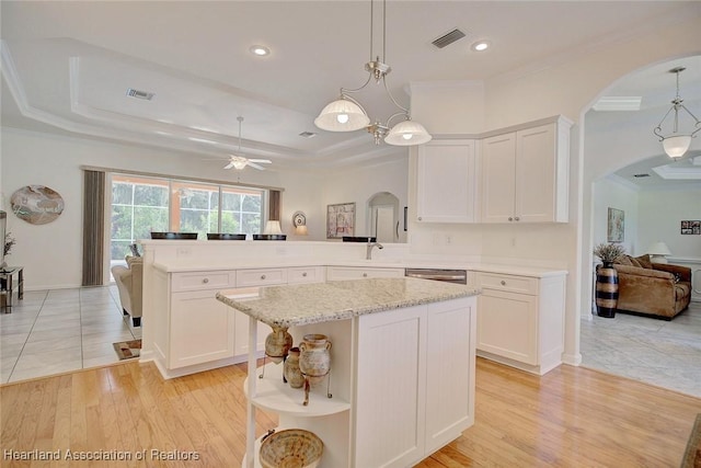 kitchen with kitchen peninsula, white cabinetry, a raised ceiling, and hanging light fixtures