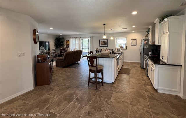 kitchen featuring open floor plan, dark countertops, white cabinets, and a center island