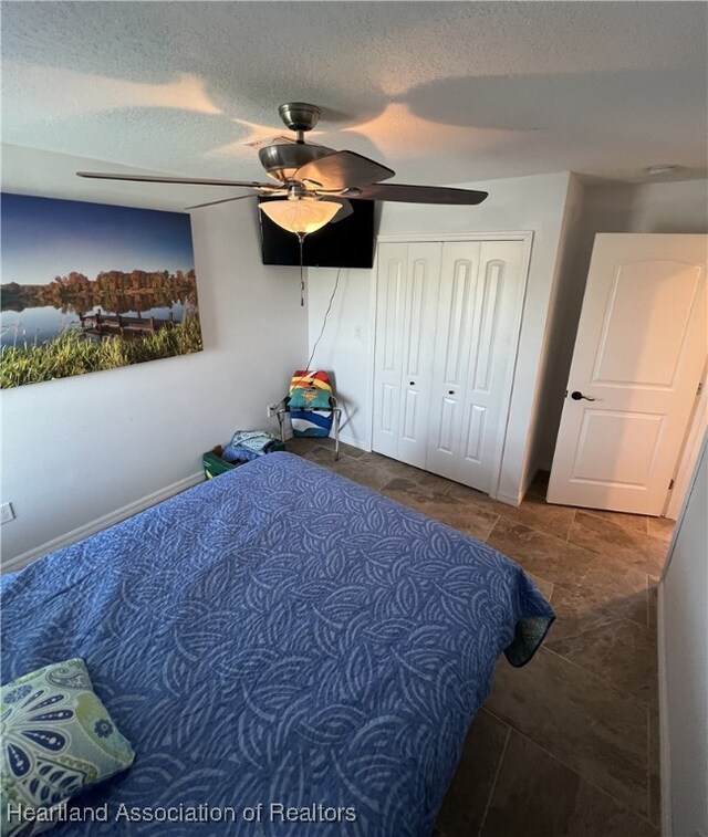 bedroom featuring a closet, baseboards, a textured ceiling, and a ceiling fan