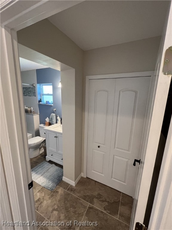 bathroom with baseboards, toilet, and vanity