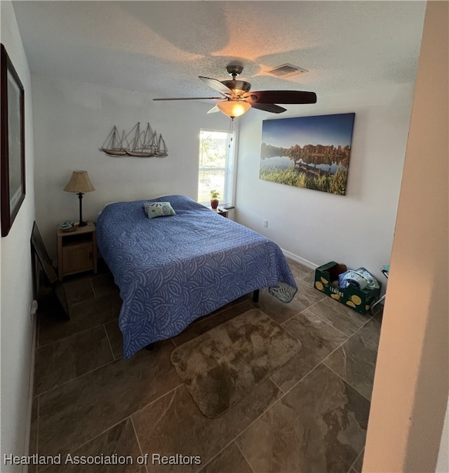 bedroom featuring visible vents, a textured ceiling, and ceiling fan