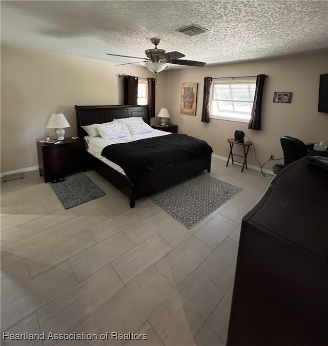 bedroom featuring visible vents, baseboards, a textured ceiling, and a ceiling fan