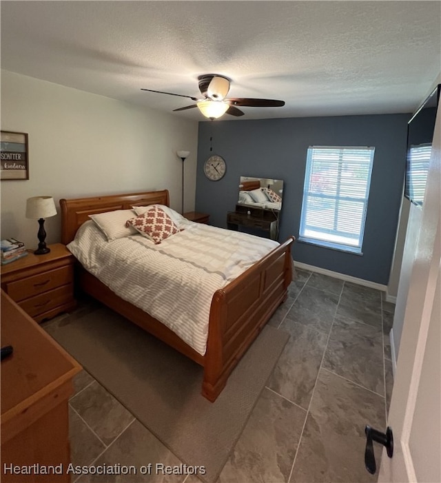 bedroom featuring baseboards, a textured ceiling, and a ceiling fan