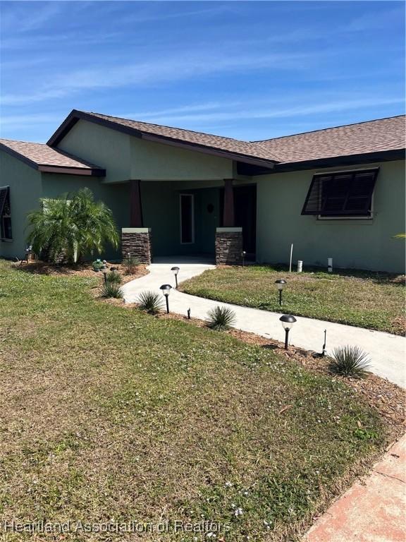 ranch-style house with stucco siding and a front yard