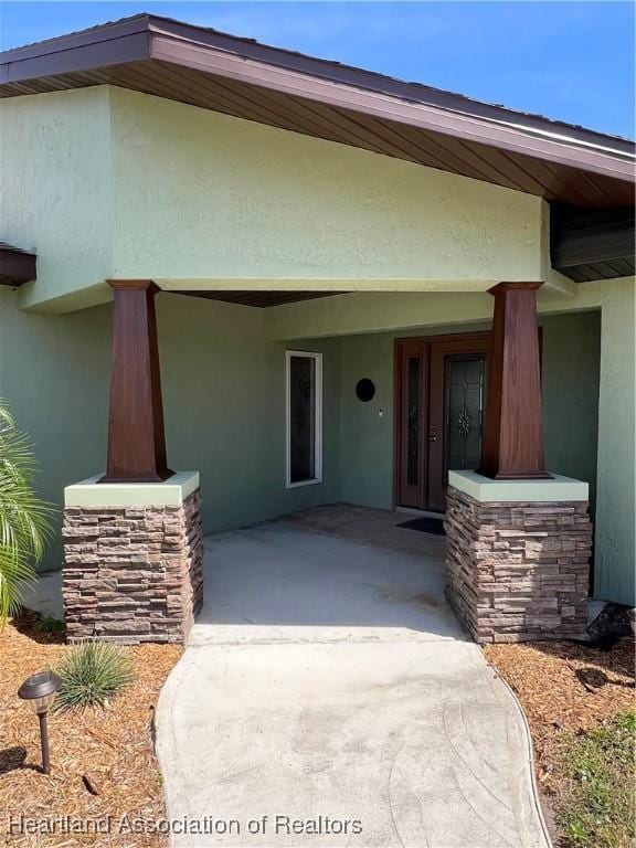 property entrance with covered porch and stucco siding