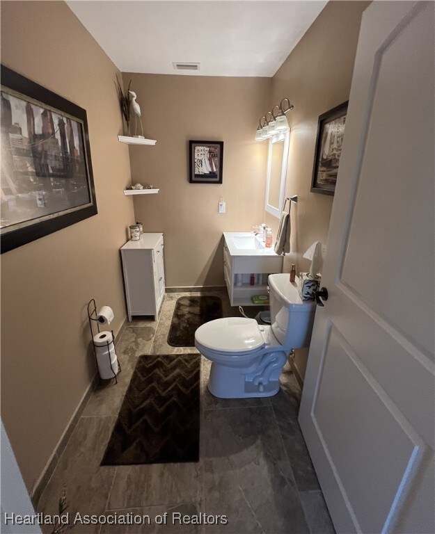 bathroom with visible vents, toilet, and baseboards